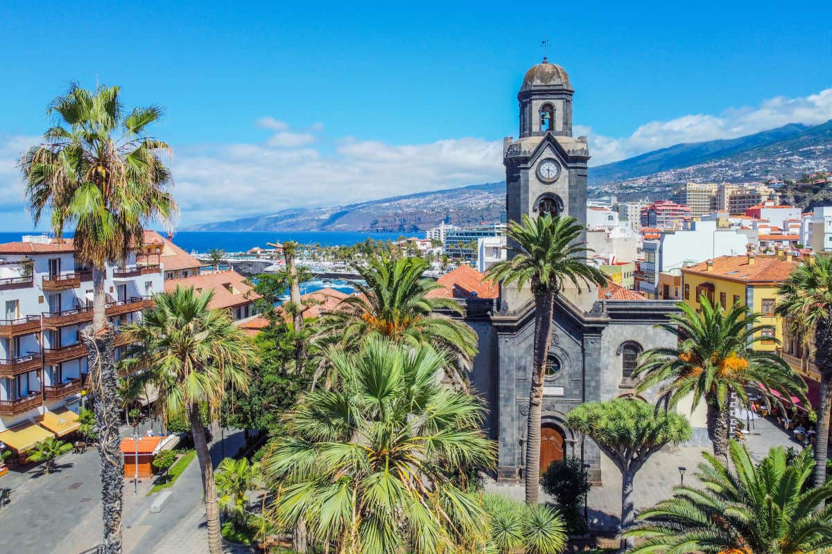 Vista aérea de una iglesia de piedra en Puerto de la Cruz con varios edificios y montañas detrás
