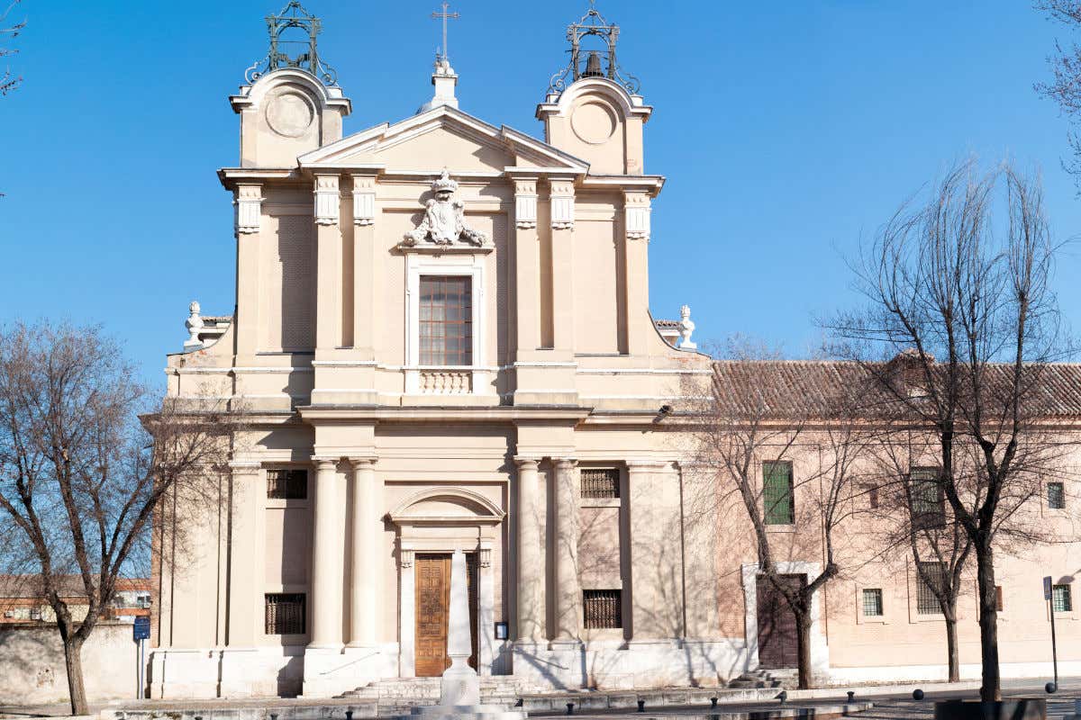 Fachada de un convento de aspecto sobrio con escasa decoración y frente a unos árboles sin hojas